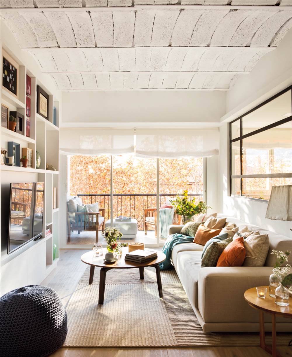 Salón blanco de piso pequeño con terraza y ventana fija que separa de la cocina