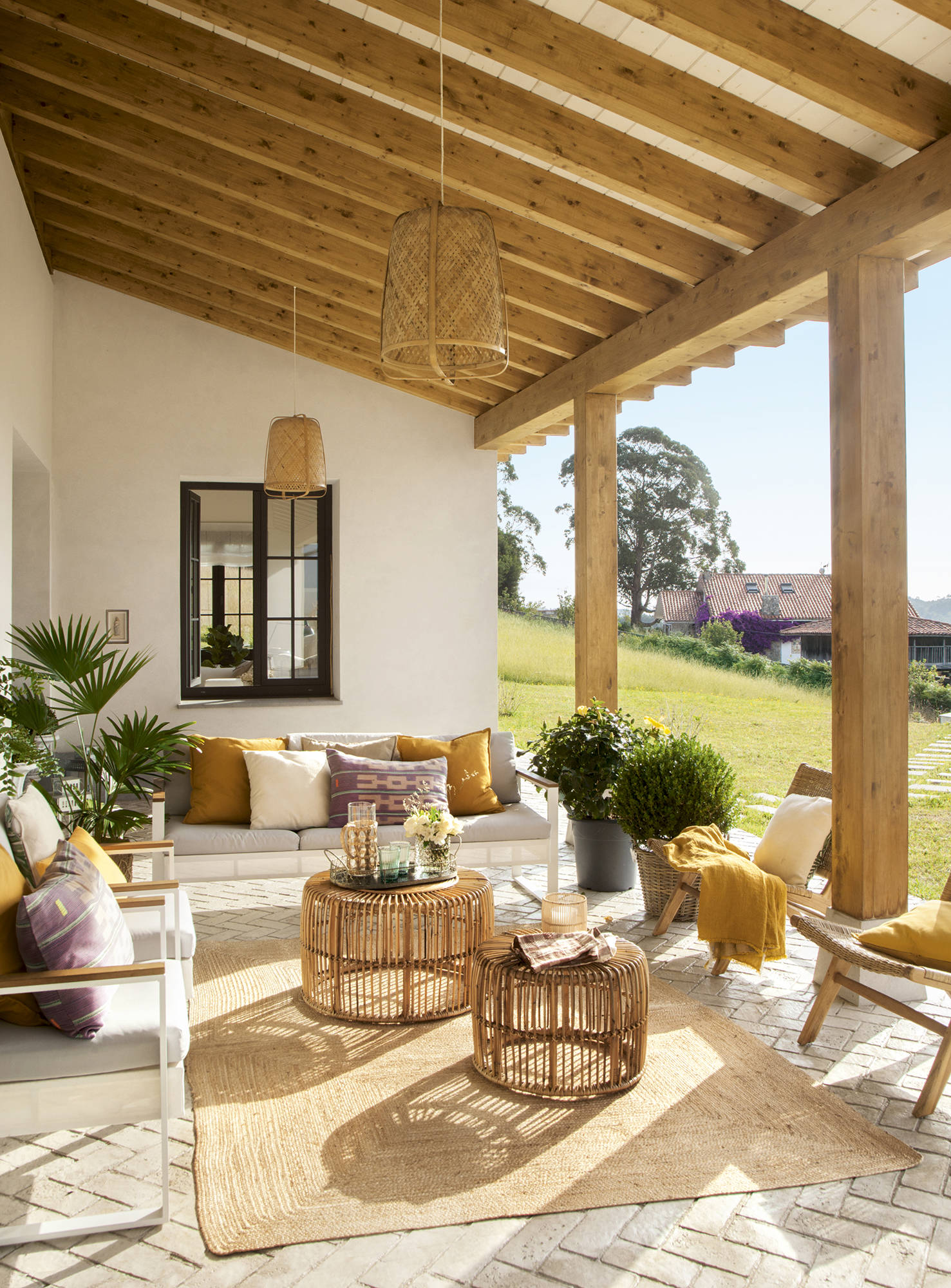 Porche con dos sofás, dos butacas y elementos decorativos de fibra y madera.